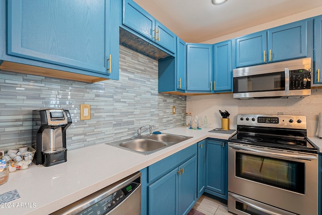 kitchen with blue cabinetry, stainless steel appliances, backsplash, and sink