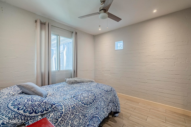 bedroom featuring ceiling fan, brick wall, and hardwood / wood-style floors