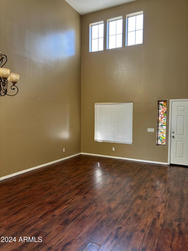 29101 N Yellow Bee Dr, San Tan Valley, AZ 85143 - empty room featuring a chandelier, dark wood finished floors, a towering ceiling, and baseboards