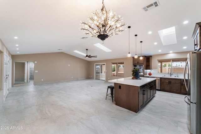 kitchen with a center island, ceiling fan with notable chandelier, sink, appliances with stainless steel finishes, and decorative light fixtures