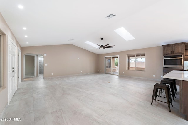 living room featuring ceiling fan and vaulted ceiling with skylight