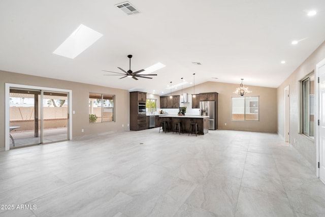 unfurnished living room with ceiling fan with notable chandelier and lofted ceiling