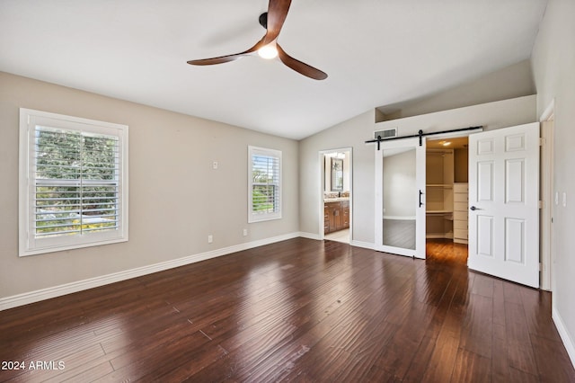 5544 E Paradise Ln, Scottsdale, AZ 85254 - unfurnished bedroom with a barn door, lofted ceiling, dark wood finished floors, a walk in closet, and ceiling fan