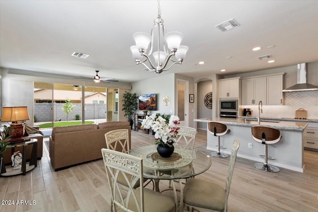dining area with arched walkways, visible vents, and ceiling fan with notable chandelier