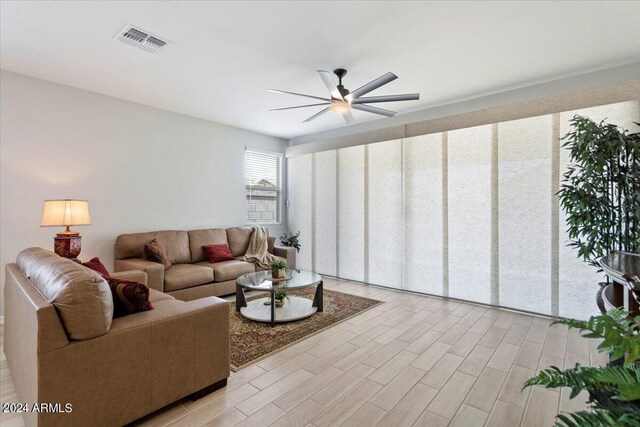 living room with ceiling fan, light wood-type flooring, and visible vents