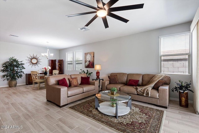living area with wood tiled floor, visible vents, baseboards, and ceiling fan with notable chandelier