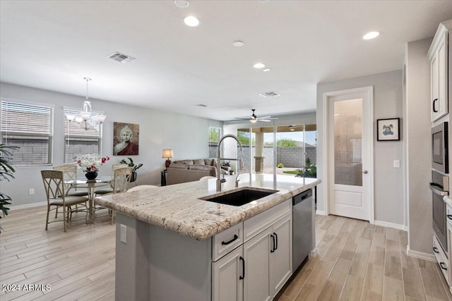 kitchen featuring light wood-type flooring, a sink, visible vents, a kitchen island with sink, and appliances with stainless steel finishes