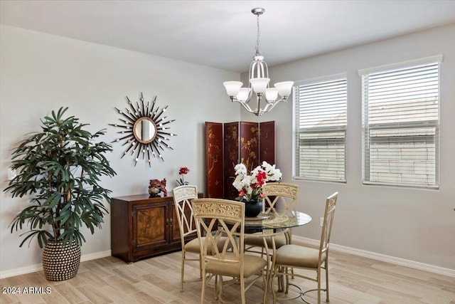 dining area with baseboards, light wood-style flooring, and a chandelier
