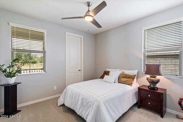 bedroom featuring light carpet, baseboards, and a ceiling fan