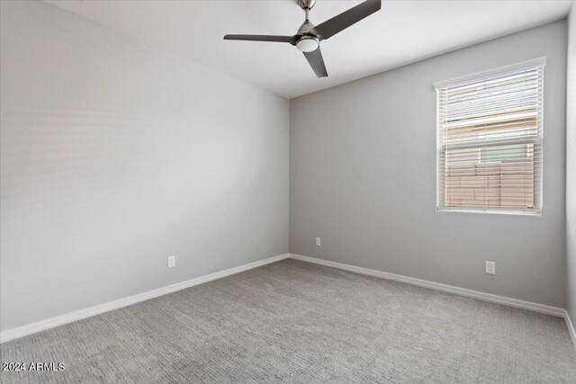 spare room with a ceiling fan, light carpet, and baseboards