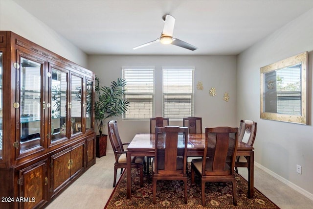 dining space featuring baseboards, ceiling fan, and light carpet