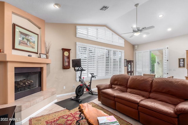 tiled living room featuring a fireplace, ceiling fan, and vaulted ceiling