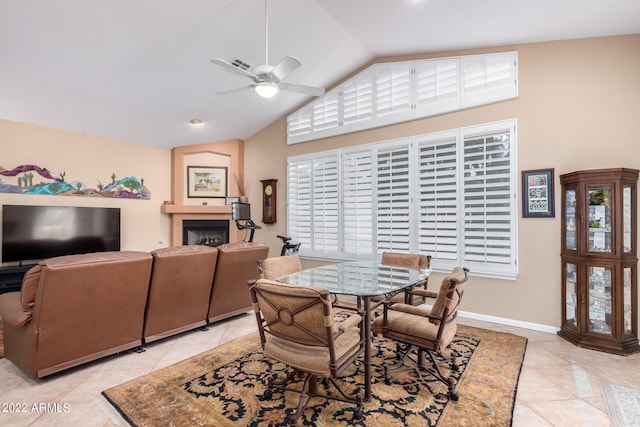 dining area featuring a fireplace, ceiling fan, light tile patterned floors, and high vaulted ceiling