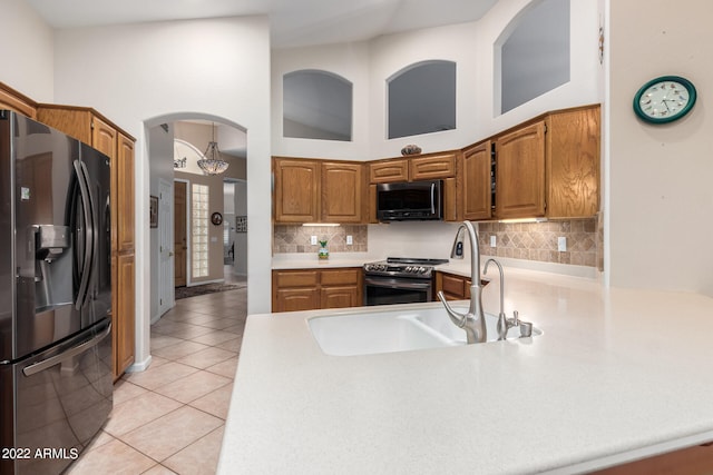 kitchen featuring sink, black appliances, tasteful backsplash, light tile patterned floors, and high vaulted ceiling