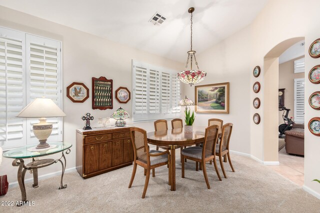 dining area featuring light colored carpet and vaulted ceiling