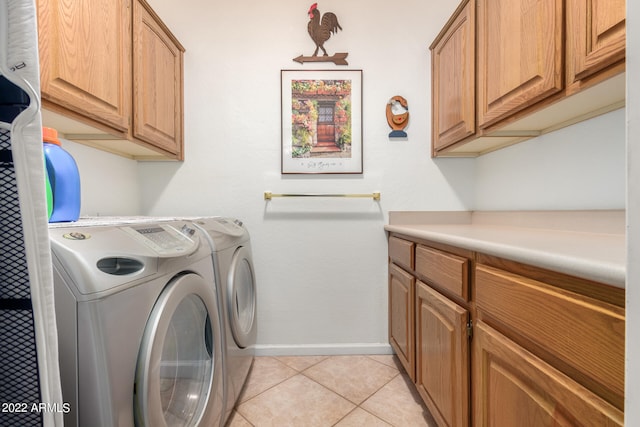 clothes washing area with washing machine and dryer, cabinets, and light tile patterned flooring