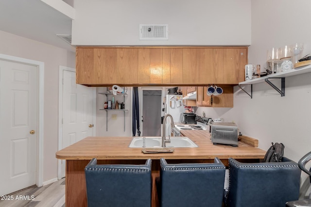 kitchen with kitchen peninsula, sink, and light hardwood / wood-style flooring