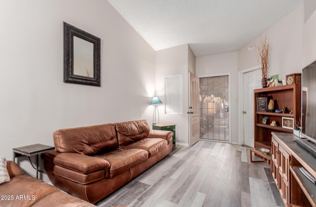 living room with light hardwood / wood-style flooring, a textured ceiling, and vaulted ceiling