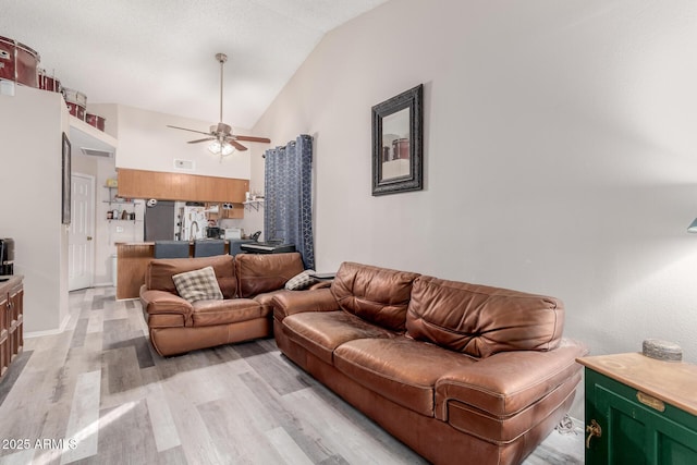 living room featuring ceiling fan, high vaulted ceiling, and light wood-type flooring