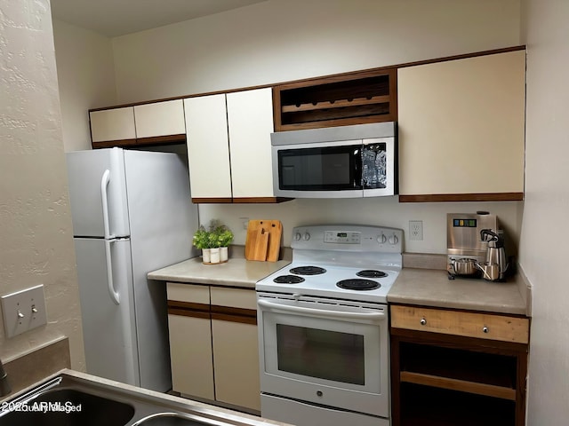 kitchen featuring white cabinetry, white appliances, light countertops, and a textured wall
