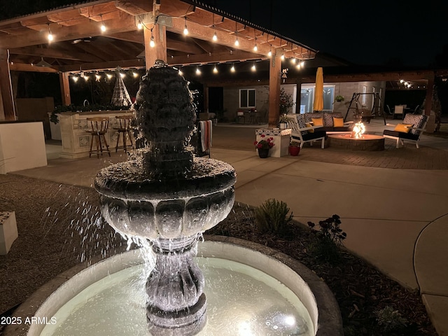 patio at night featuring a fire pit and exterior bar