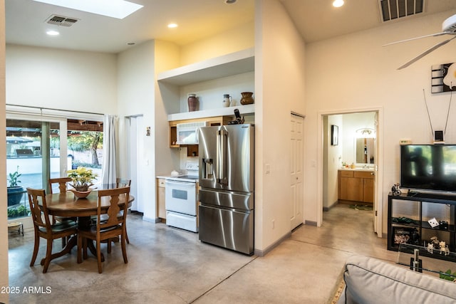 kitchen featuring white range with electric cooktop, stainless steel refrigerator with ice dispenser, a high ceiling, and a skylight