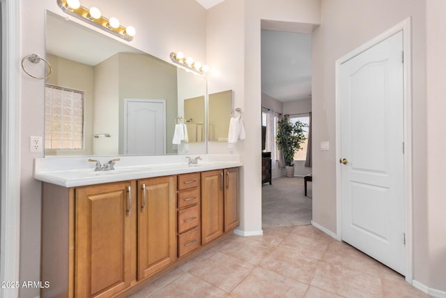 full bath featuring baseboards, double vanity, tile patterned floors, and a sink