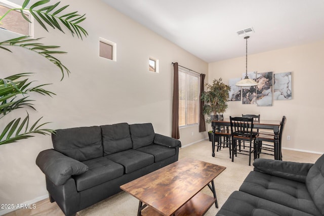 living room with visible vents, baseboards, and light colored carpet