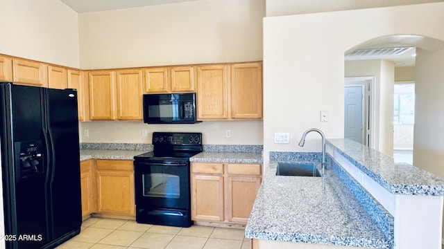 1630 W Pecan Rd, Phoenix, AZ 85041 - kitchen with black appliances, a peninsula, light tile patterned floors, light brown cabinetry, and arched walkways