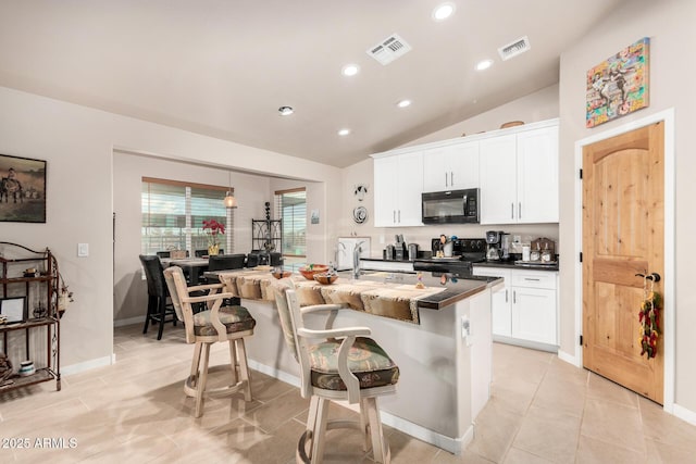 kitchen with black appliances, a breakfast bar, white cabinets, and a center island with sink