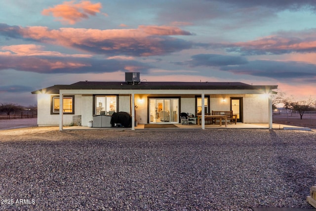 back house at dusk featuring cooling unit and a patio area