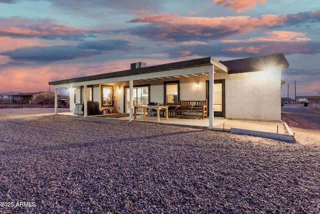 back house at dusk featuring a patio