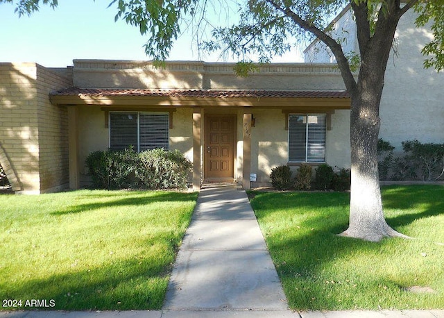 view of front facade featuring a front lawn, a tiled roof, and stucco siding