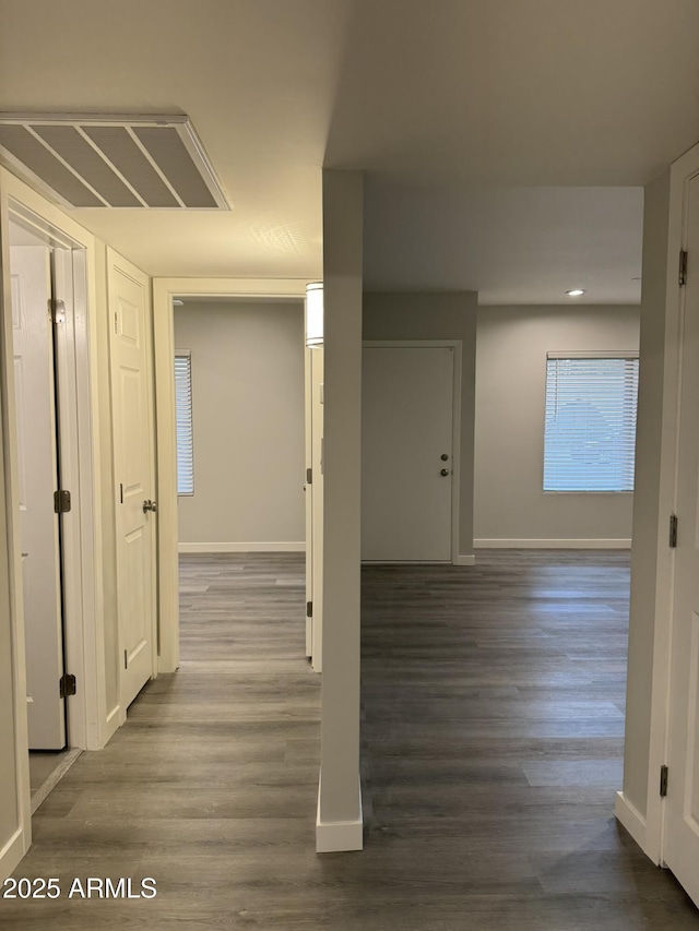 hall featuring wood finished floors, visible vents, and baseboards