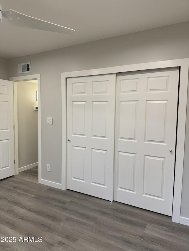 unfurnished bedroom featuring dark wood-style flooring, baseboards, visible vents, and a closet