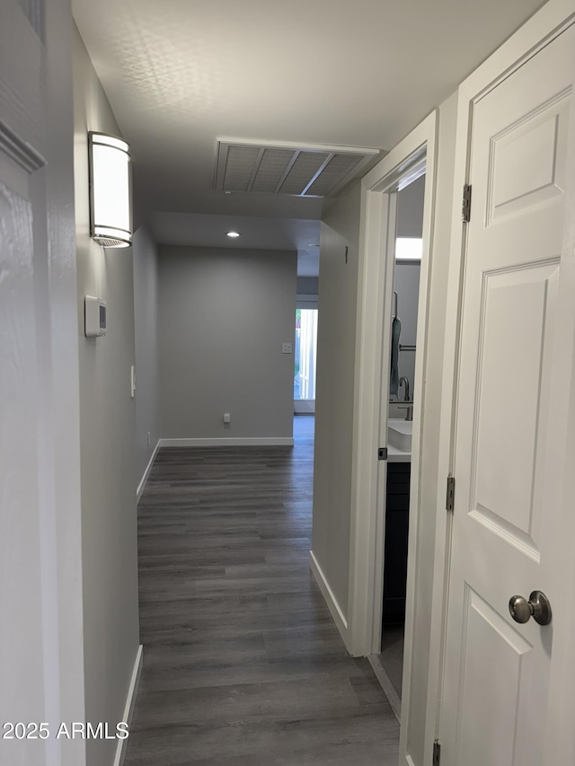 hall featuring visible vents, dark wood-type flooring, and baseboards