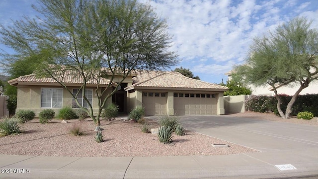 view of front of home with a tile roof, an attached garage, driveway, and stucco siding