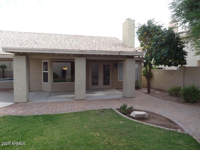 rear view of property with a patio, french doors, fence, and stucco siding