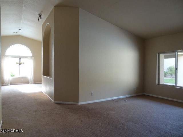 carpeted empty room with vaulted ceiling, plenty of natural light, baseboards, and a chandelier