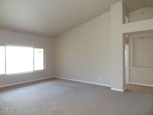 spare room with baseboards, carpet floors, and high vaulted ceiling