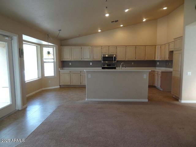 kitchen featuring visible vents, high vaulted ceiling, a kitchen island with sink, stainless steel appliances, and light countertops