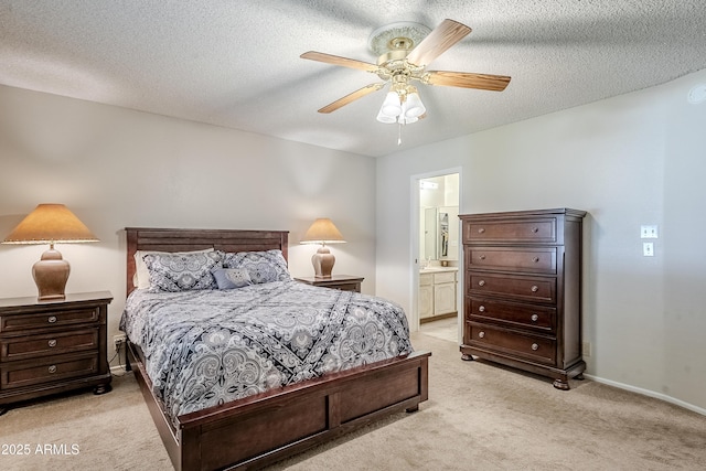 bedroom with ceiling fan, ensuite bath, light carpet, and a textured ceiling