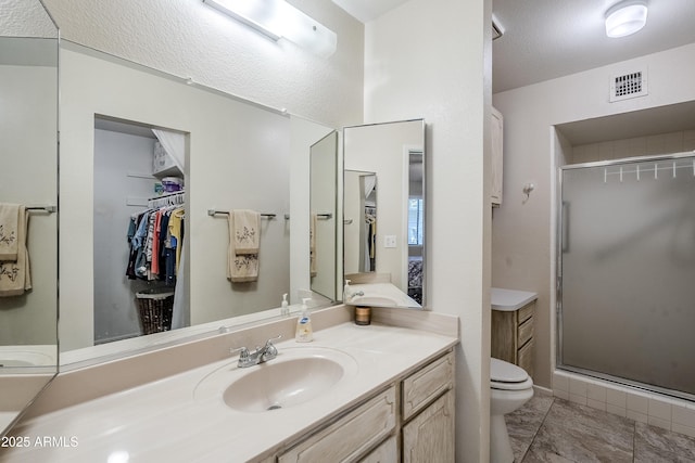 bathroom with an enclosed shower, vanity, toilet, and a textured ceiling