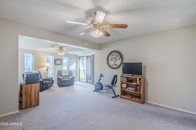 living area with ceiling fan, carpet, and a textured ceiling