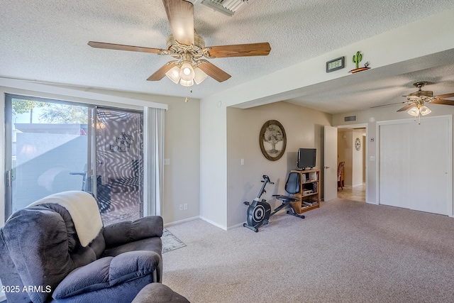 living area with light carpet, ceiling fan, and a textured ceiling