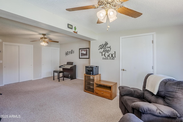 living room featuring a textured ceiling, ceiling fan, and light colored carpet