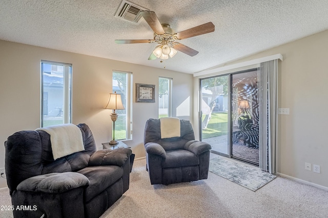 living room with ceiling fan, a healthy amount of sunlight, light carpet, and a textured ceiling