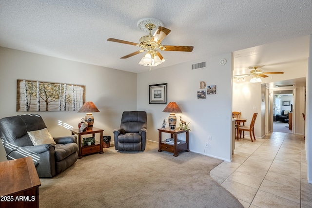 sitting room featuring ceiling fan, light colored carpet, and a textured ceiling