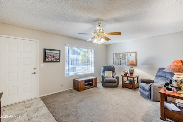 living area with ceiling fan, light tile patterned floors, and a textured ceiling