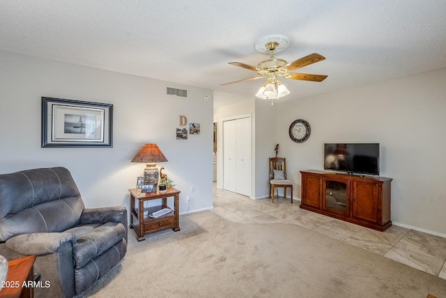 sitting room featuring ceiling fan, light colored carpet, and a textured ceiling